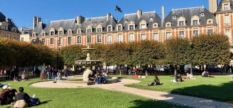 people enjoying a beautiful day on the green grass at Place des Vosges