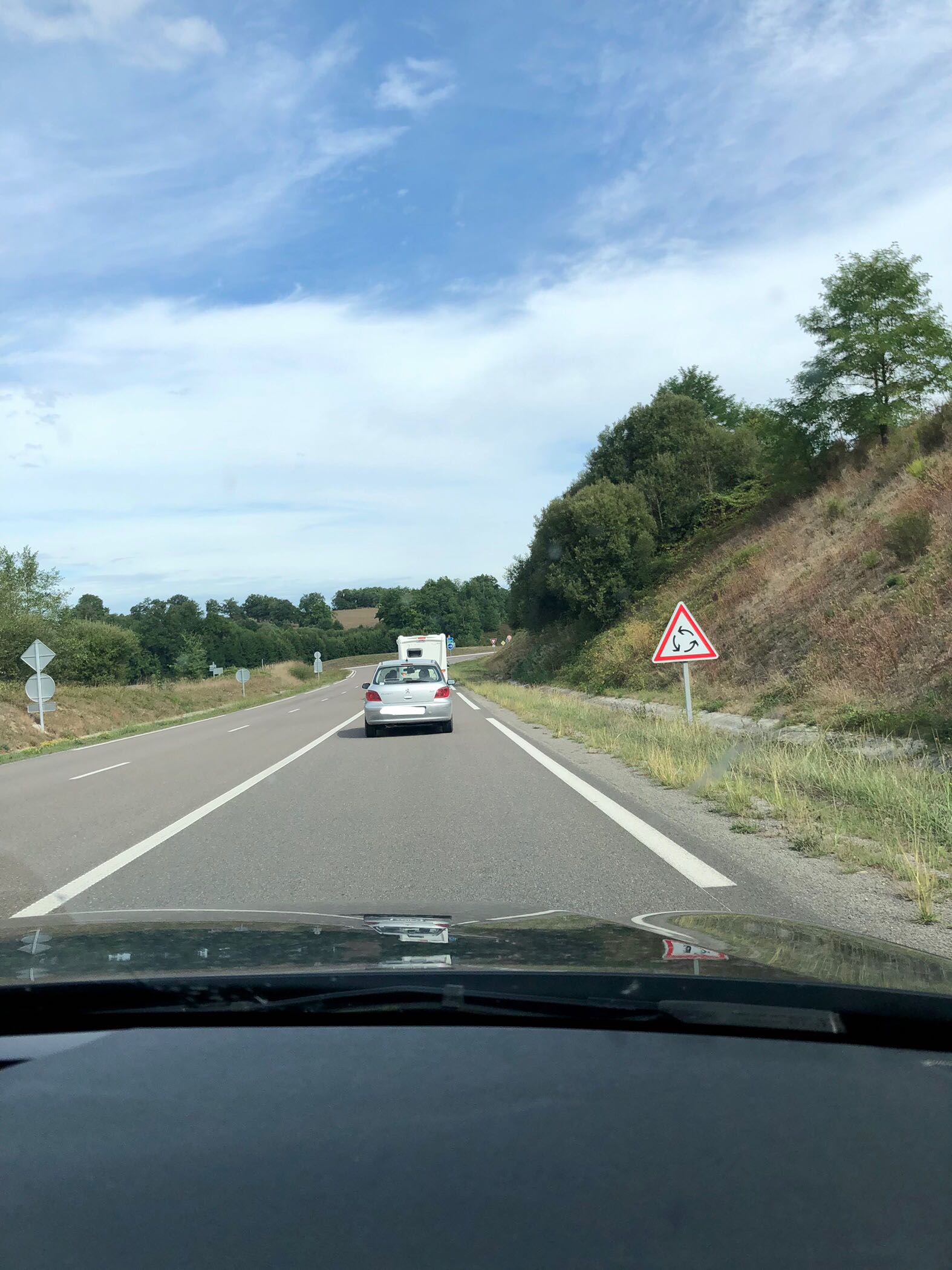 white triangular sign with red border and three black arrows indicating an upcoming roundabout in France