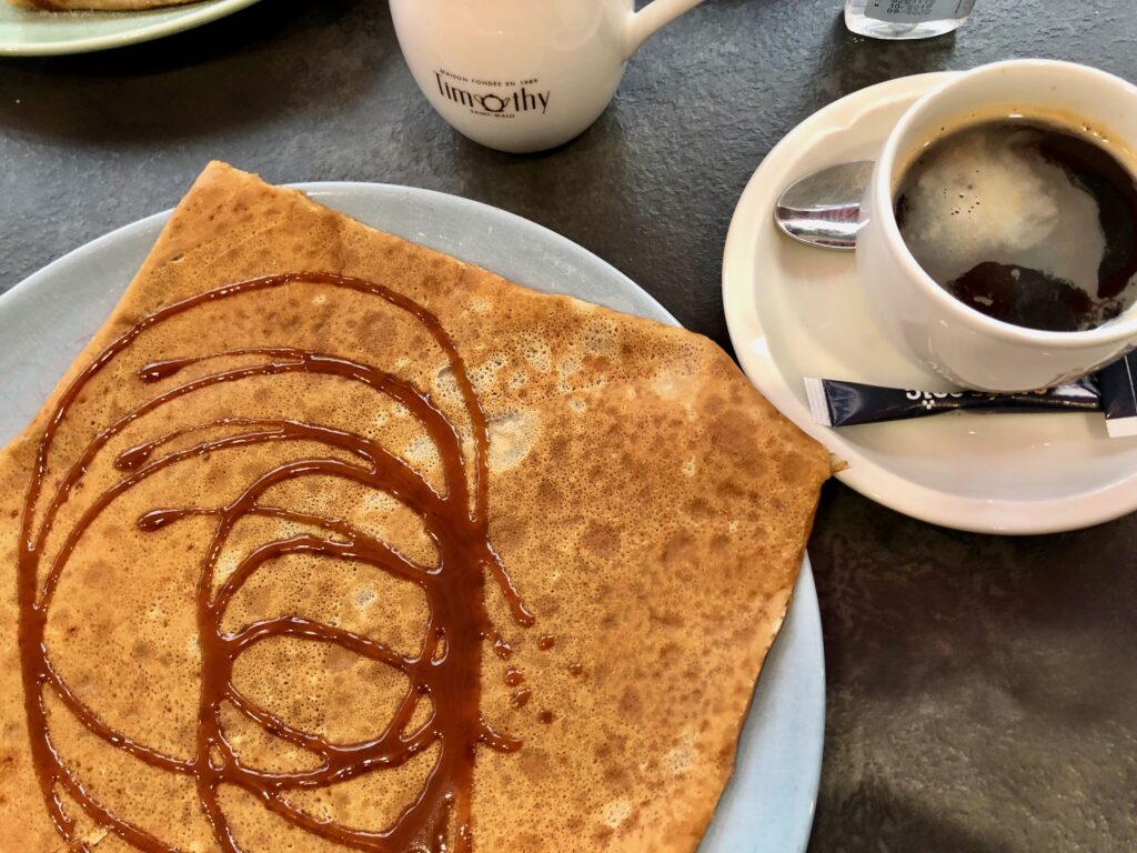 a dessert crêpe drizzled with caramel au beurre salé, a specialty of Bretagne, alongside a long black coffee