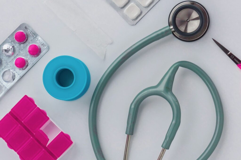 Doctor's supplies: stethoscope, pills, scissors, and tape on a table