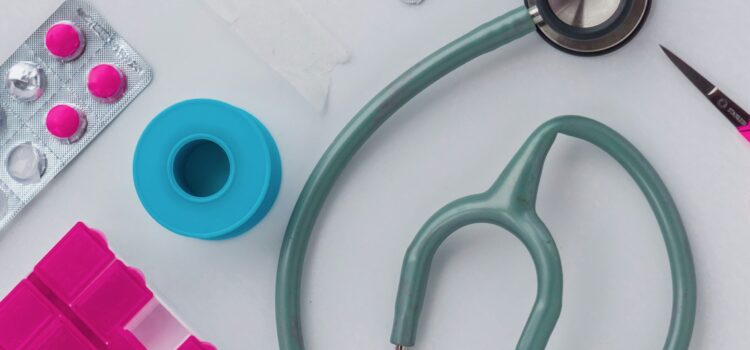 Doctor's supplies: stethoscope, pills, scissors, and tape on a table