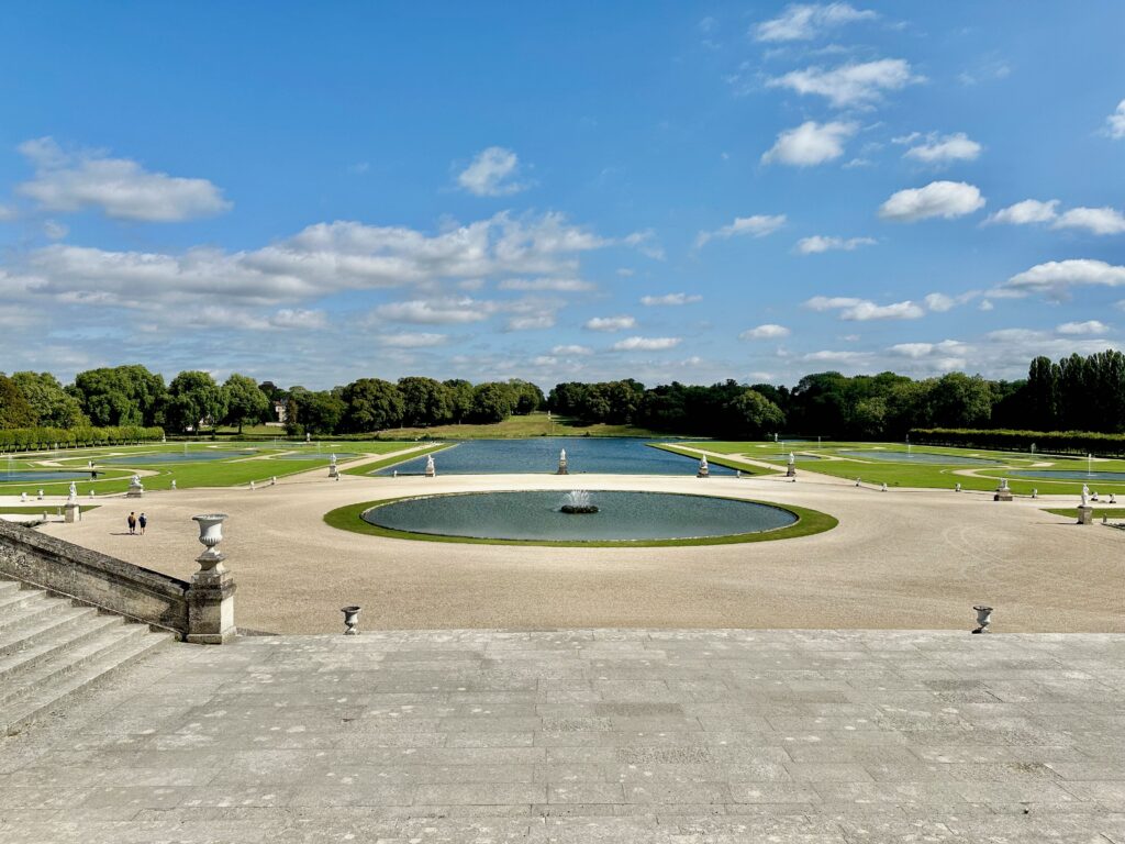 Looking out over Domaine de Château de Chantilly, showing some water features and green grass